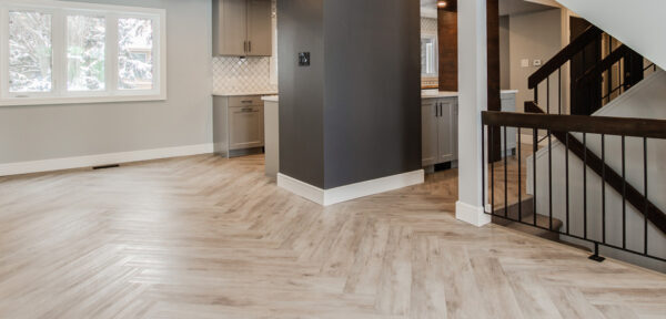 Open-concept great room in a new-build style home with upgraded herringbone flooring